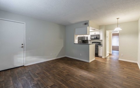 A room with a white door and a kitchenette in the corner.