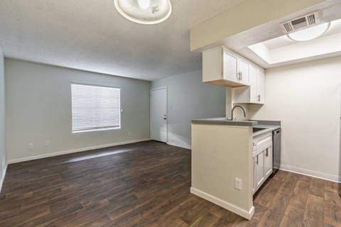 A kitchen area with wooden floors and white cabinets.