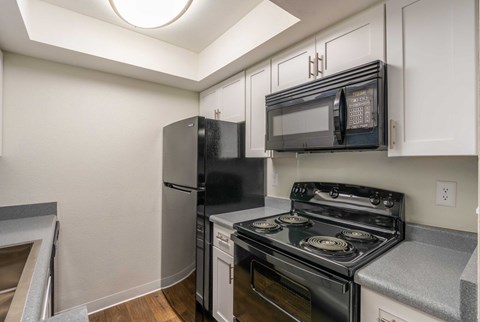 A kitchen with a black fridge, black microwave, and a black stove.