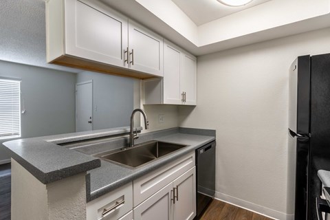 A kitchen with white cabinets and a black refrigerator.