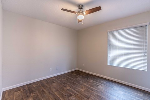A room with a ceiling fan and wooden flooring.