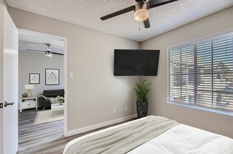 A bedroom with a large bed and a flat screen TV mounted on the wall.