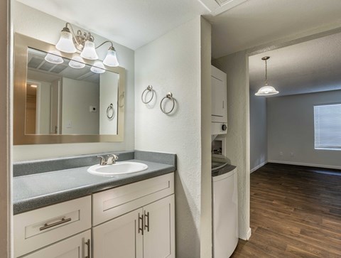 A bathroom with a sink, mirror, and towel rack.