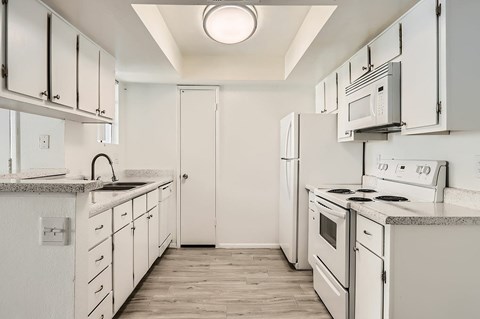 A white kitchen with a sink and stove.