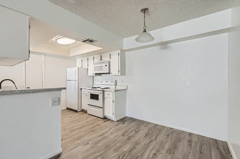 A kitchen with white appliances and wooden floors.