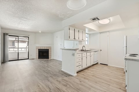 A spacious kitchen with white cabinets and a fireplace.