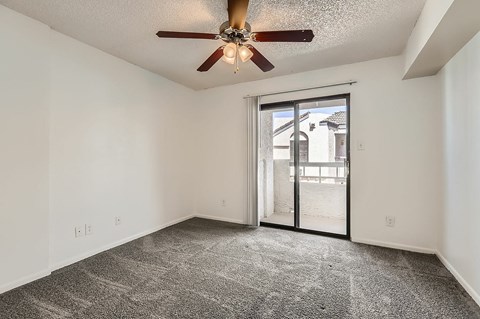 A room with a ceiling fan and a door leading outside.