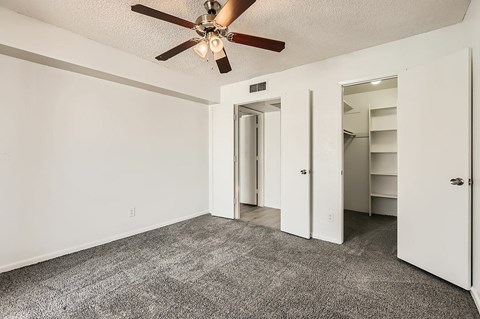 A room with a ceiling fan and carpeted floor.