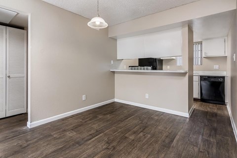 A kitchen area with a black trash bin and a wooden floor.