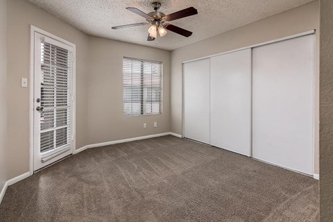 A room with a ceiling fan and a door with blinds.