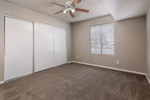 A room with a ceiling fan and sliding doors.
