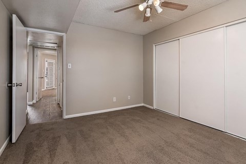 A room with a carpeted floor and a ceiling fan.