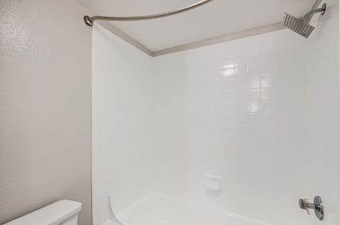 A white bathroom with a toilet, tub, and shower.
