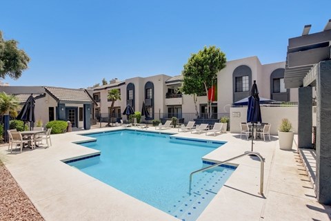 A swimming pool surrounded by lounge chairs and umbrellas.