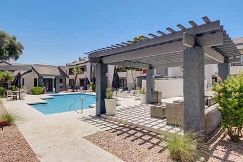 A pool area with a pergola and a pool.