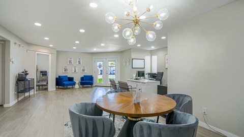 A modern living room with a round wooden table and grey chairs.