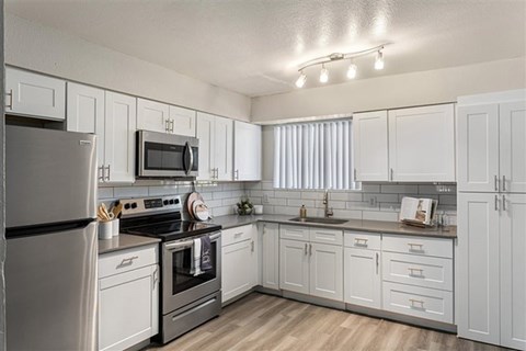 A kitchen with white cabinets and appliances.