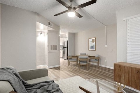 A living room with a grey couch and a fan.