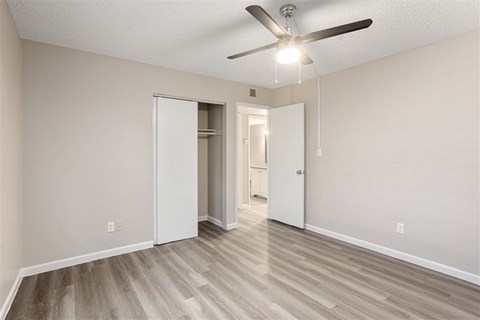 A room with a ceiling fan and light fixture, and a doorway leading to another room.