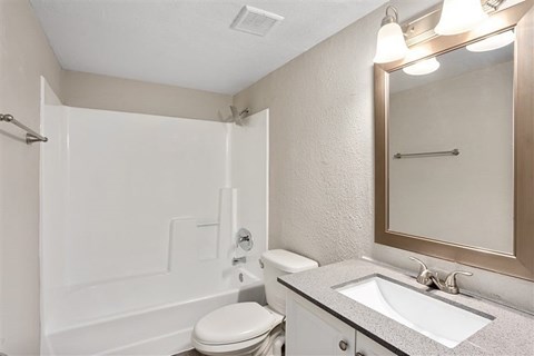 A white bathroom with a toilet, sink, and shower.