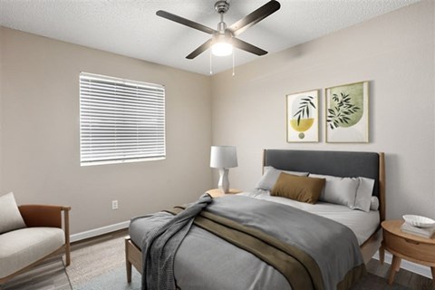 A bedroom with a bed, chair, and ceiling fan.