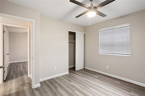 A room with a ceiling fan and a window with blinds.