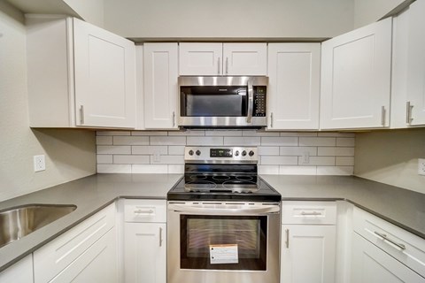 A modern kitchen with white cabinets and stainless steel appliances.