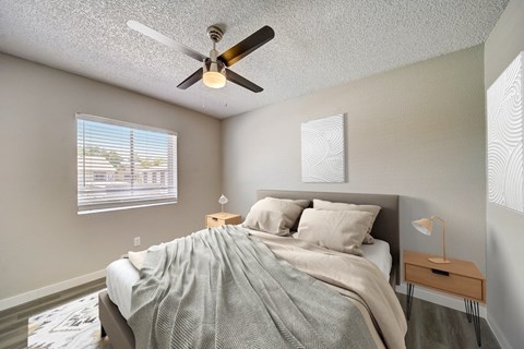 A bedroom with a bed, nightstand, and a ceiling fan.