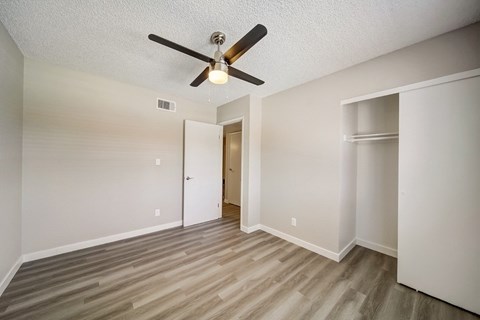 A room with a ceiling fan and wood flooring.