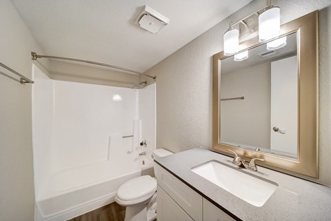 A bathroom with a white toilet, sink, and mirror.