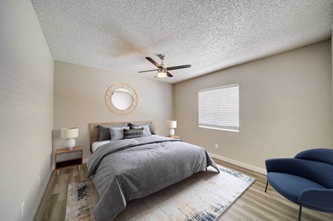 A bedroom with a bed, a chair, and a ceiling fan.