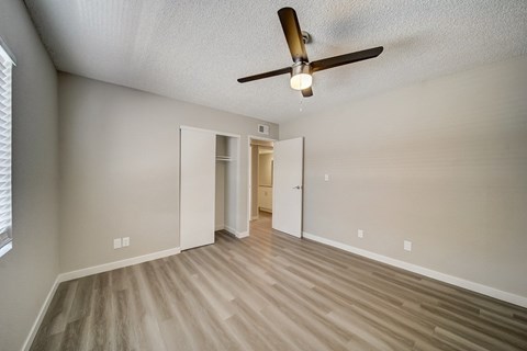 A room with a ceiling fan and light fixture, and a doorway leading to another room.