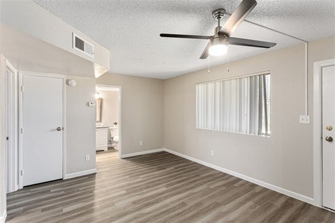 A room with a ceiling fan and light fixture, and a door on the left.