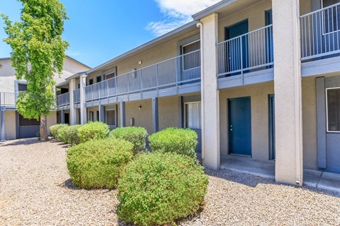 A building with a balcony and bushes in front.