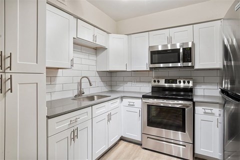 A modern kitchen with white cabinets and stainless steel appliances.