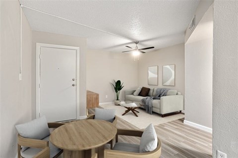 A living room with a white couch, a wooden table, and a ceiling fan.