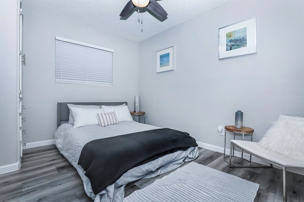 A bedroom with a bed, a chair, and a ceiling fan.