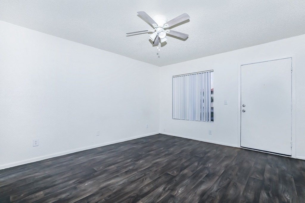 A room with a ceiling fan and wooden flooring.
