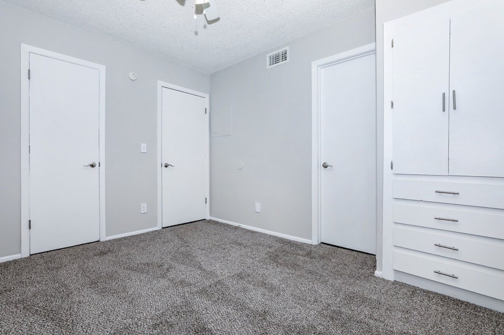 A room with white doors and a grey carpet.