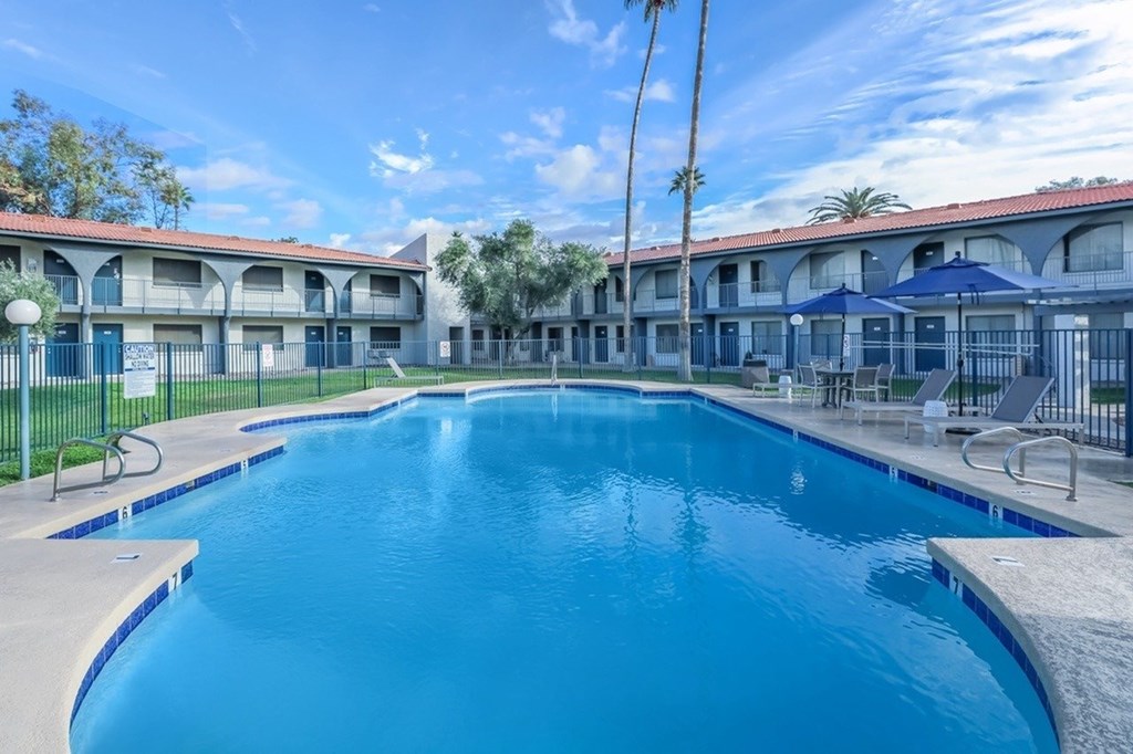 A large blue swimming pool in front of a building with a fence around it.