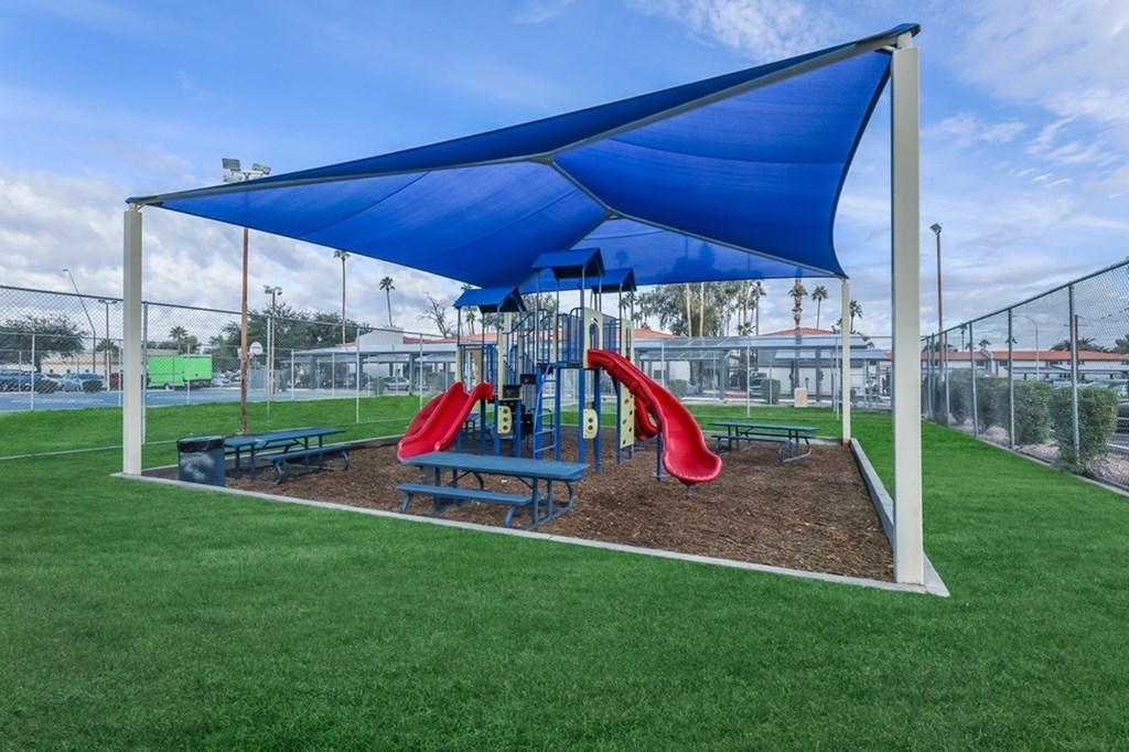 A playground with a blue canopy and a red slide.