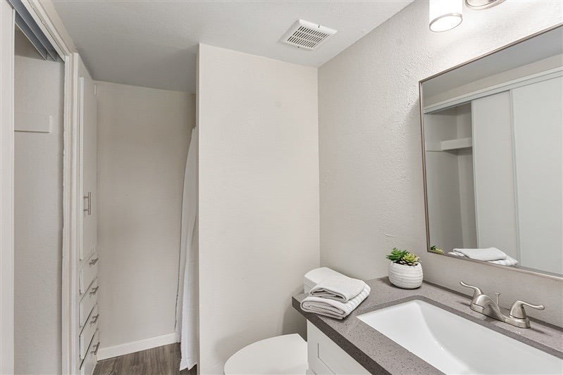 A white bathroom with a sink, mirror, and towel.