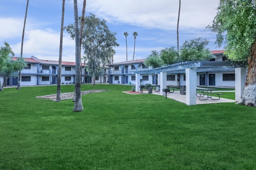 A grassy area with trees and benches in front of a building.
