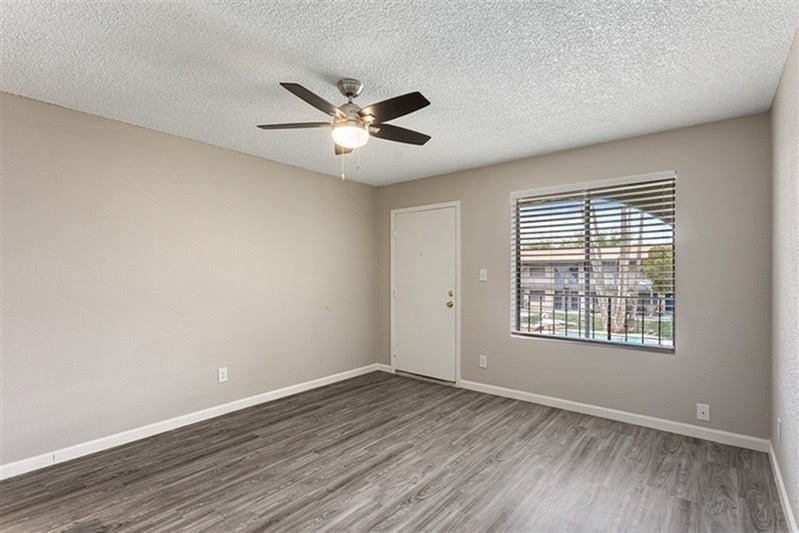A room with a ceiling fan and a window with blinds.
