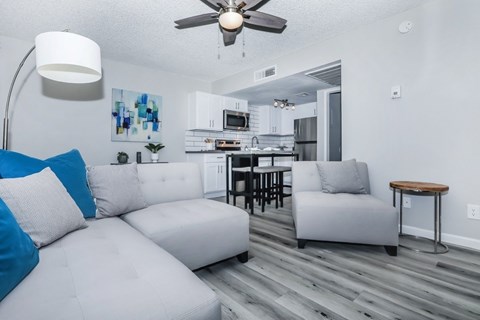 A modern living room with a white couch and a kitchen in the background.