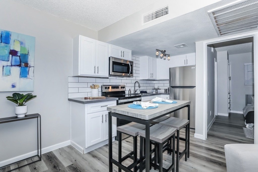 A kitchen with white cabinets and a wooden table.