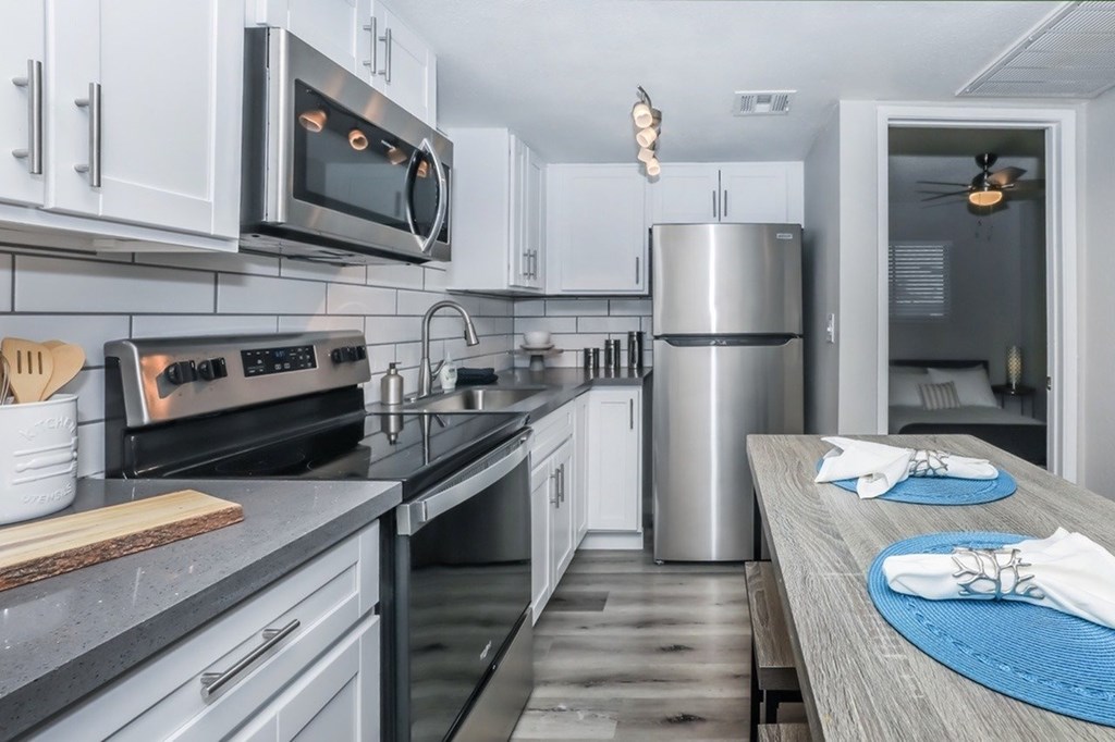 A modern kitchen with a stainless steel refrigerator and a microwave above the oven.
