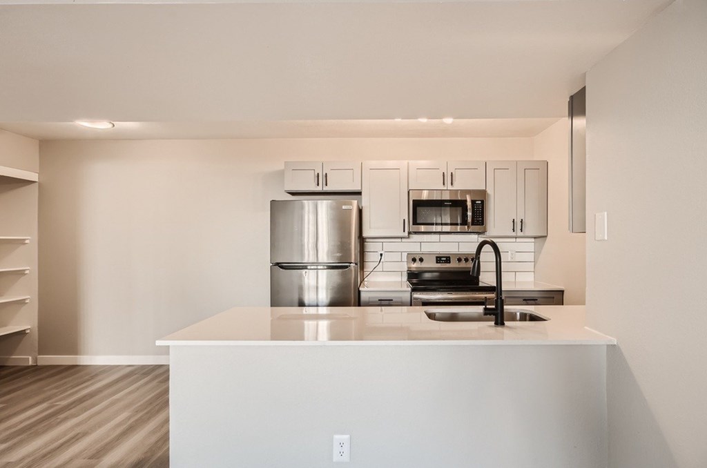 A modern kitchen with a white countertop and stainless steel appliances.