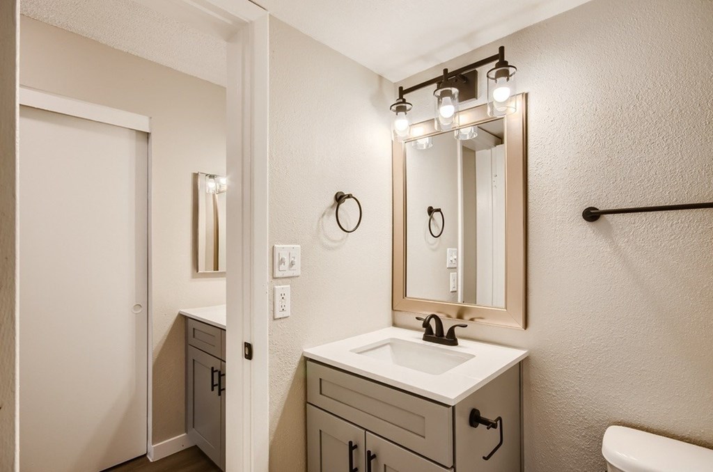 A bathroom with a sink, mirror, and towel rack.