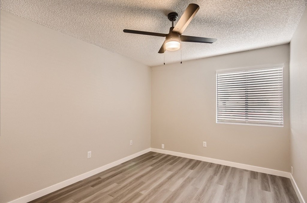 A room with a ceiling fan and a window with blinds.